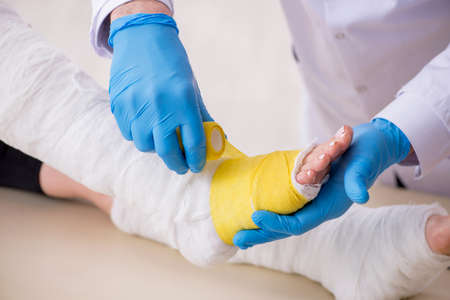 Young injured woman visiting old doctor traumatologistの写真素材