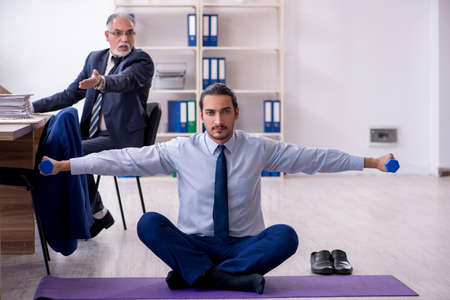 Two employees doing physical exercises at workplaceの写真素材