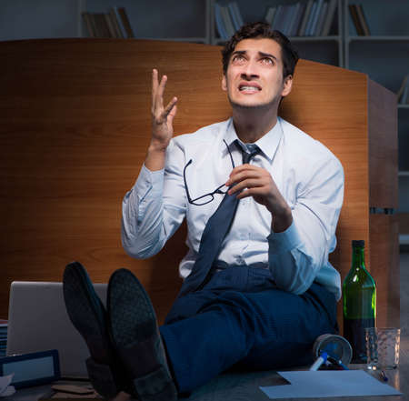 Stressed businessman working overtime in depressionの写真素材