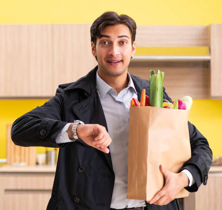 Young handsome man with vegetables in kitchenの写真素材