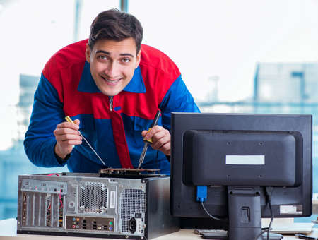 Computer technician repairing broken computer in workshopの写真素材
