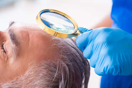 Old man visiting young male doctor in hair transplantation conceptの写真素材