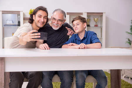 Grandfather learning new technology from son and grandsonの写真素材