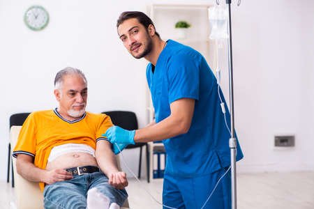 Old man visiting young male doctorの写真素材