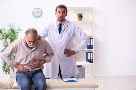 Old patient visiting young male doctorの写真素材