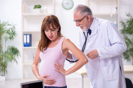 Young pregnant woman visiting old male doctor gynecologist