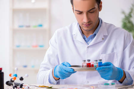 Young male lab assistant in drug synthesis concept