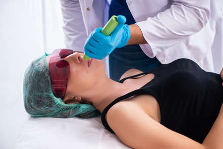 Young woman visiting male doctor dermatologistの写真素材