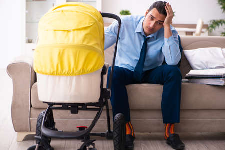 Young businessman looking after newborn at homeの写真素材