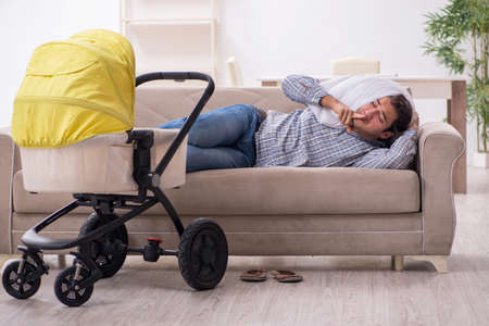 Young father looking after newborn baby at homeの写真素材