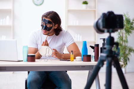 Young male cosmetician recording video for his blogの写真素材
