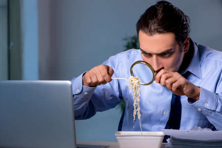 Hungry employee working late in the officeの写真素材