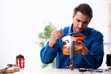Young male repairman repairing violinの写真素材