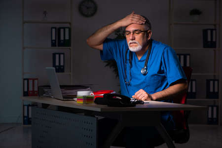 Aged male doctor in the hospital at nightの写真素材