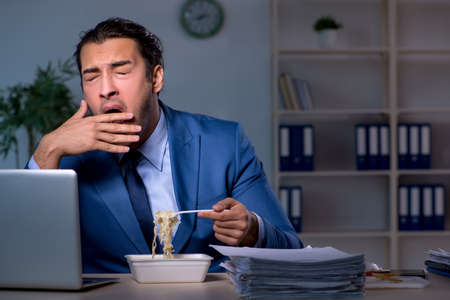 Hungry employee working late in the officeの写真素材