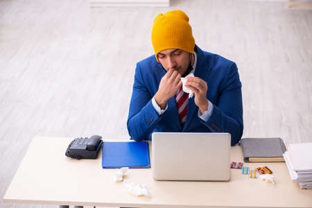 Sick male employee suffering at workplace from coronavirusの写真素材