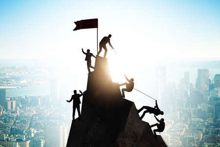 Concept of teamwork with team climbing mountain top
