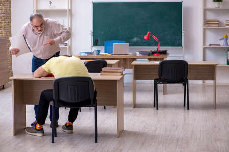 Old teacher and young male student in the classroomの写真素材