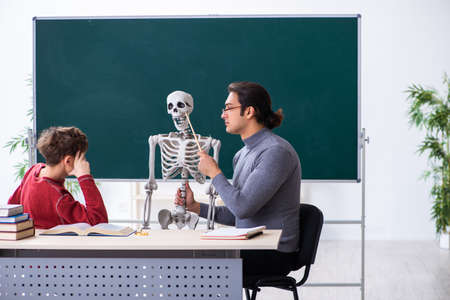 Young male teacher and schoolboy in the classroomの写真素材