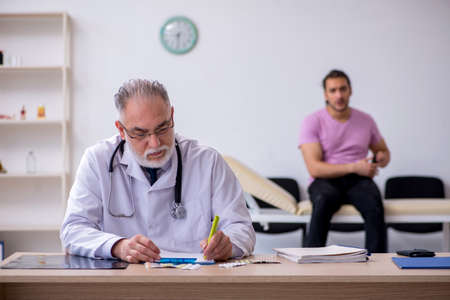 Young male patient visiting old male doctorの写真素材