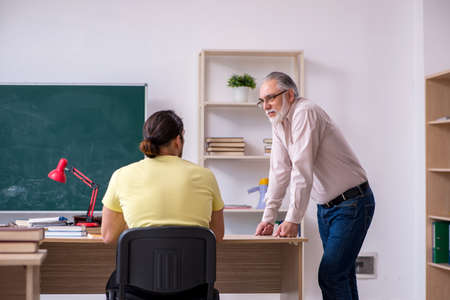 Old teacher and young male student in the classroomの写真素材