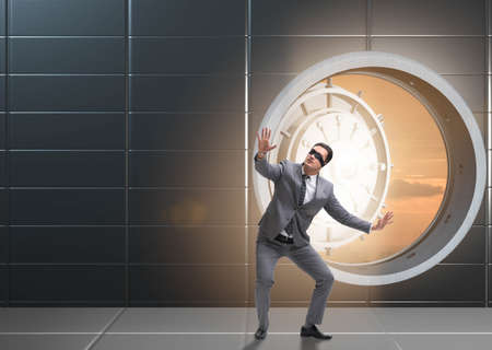 Blindfolded businessman in front ot vault doorの写真素材