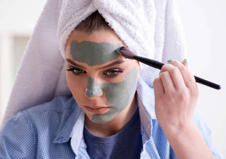 Woman applying clay mask with brush at homeの写真素材