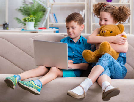 Two kids sitting at laptop at homeの写真素材