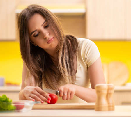 Young woman preparing salad at home in kitchenの写真素材