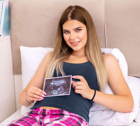 Happy young pregnant woman in the bed