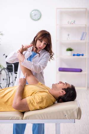 Injured man visiting young female doctor osteopathの写真素材