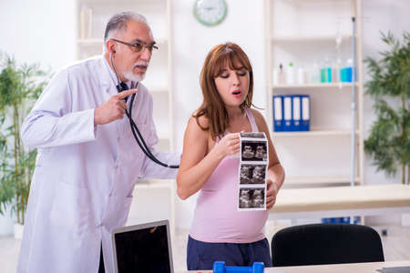Young pregnant woman visiting old male doctor gynecologist