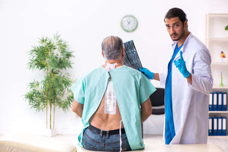 Old man visiting young male doctorの写真素材