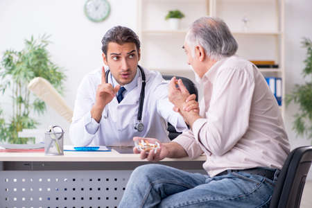 Young male doctor and old patient in antismoking conceptの写真素材