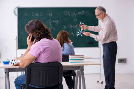 Old chemist teacher and two students in the classroomの写真素材