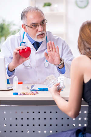 Young woman visiting old male doctorの写真素材