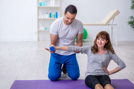 Young woman doing sport exercises with personal coachの写真素材