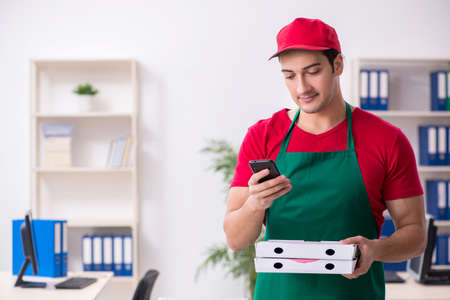 Young male courier delivering pizza to the officeの写真素材