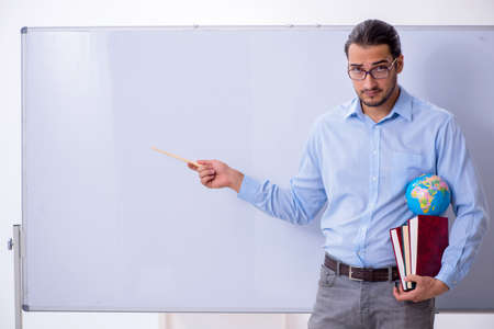 Young male geography teacher in front of whiteboardの写真素材