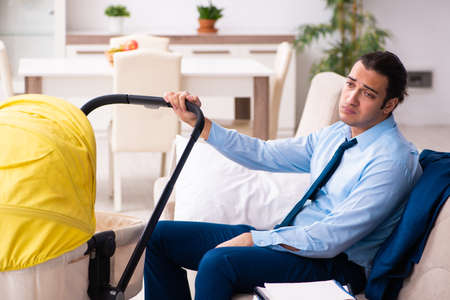 Young businessman looking after newborn at homeの写真素材