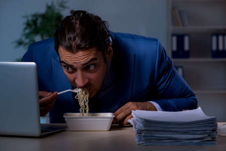 Hungry employee working late in the officeの写真素材