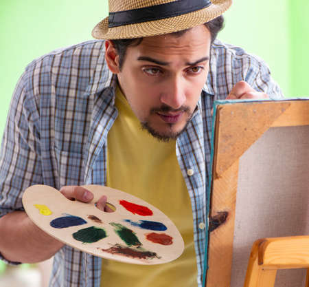 Young male artist working on new painting in his studioの写真素材