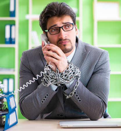 Employee chained to his desk due to workloadの写真素材