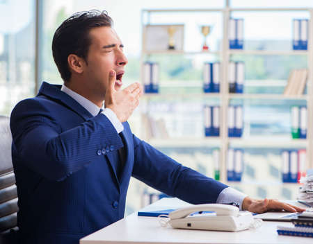 Young handsome businessman employee working in office at deskの写真素材