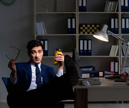 Employee working late and drinking strong coffee to stay awakeの写真素材