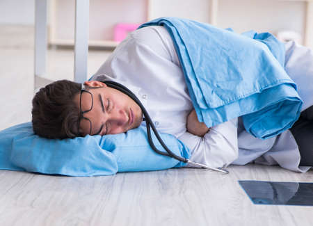 Doctor sleeping on floor after long night shiftの写真素材