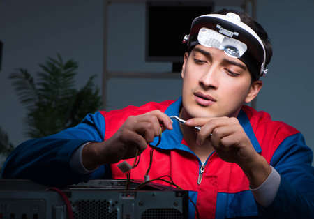 Computer specialist repairing PC late at night