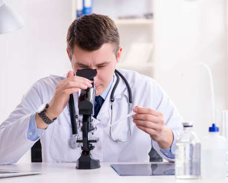 Male doctor looking at lab results in hospitalの写真素材