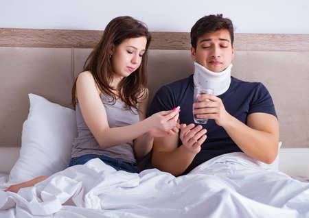 Loving wife taking care of injured husband in bedの写真素材
