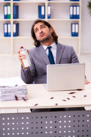 Young male employee and too many cockroaches in the officeの写真素材